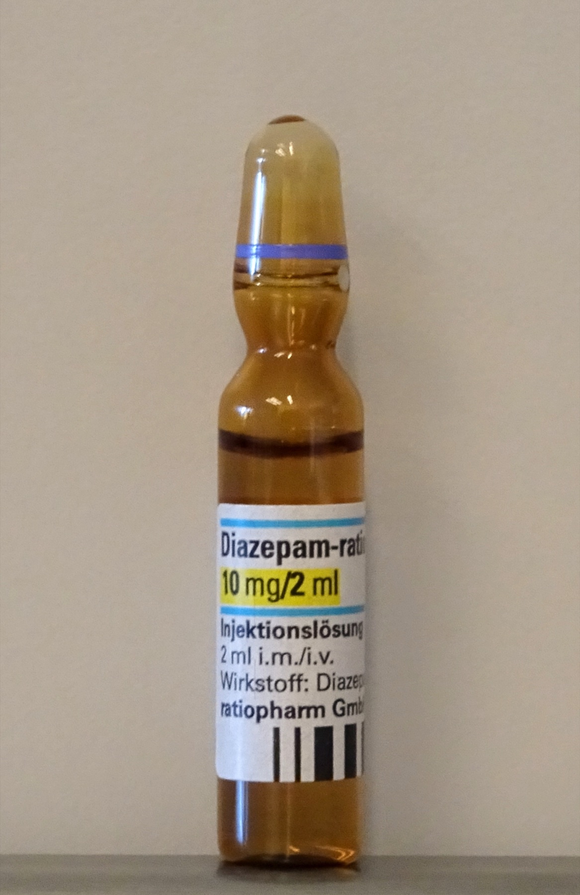 Ampola de vidro de diazepam 10 miligramas em 2 mililitros, benzodiazepínico injetável, fotografada em fundo neutro com rótulo legível.