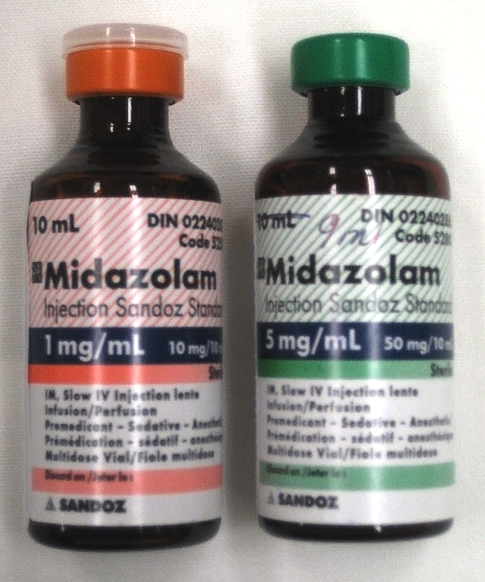 Dois frascos de vidro de midazolam injetável Sandoz: à esquerda 1 mg por mL (tampa laranja) e à direita 5 mg por mL (tampa verde); rótulos legíveis com via intramuscular e intravenosa lenta.