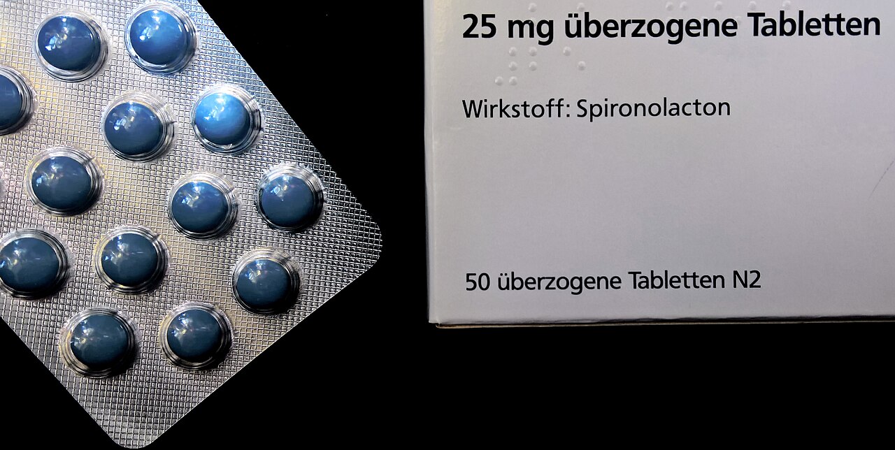Embalagem e blísteres de espironolactona em comprimidos revestidos de 25 mg, com o nome do princípio ativo e a dosagem legíveis na cartonagem.
