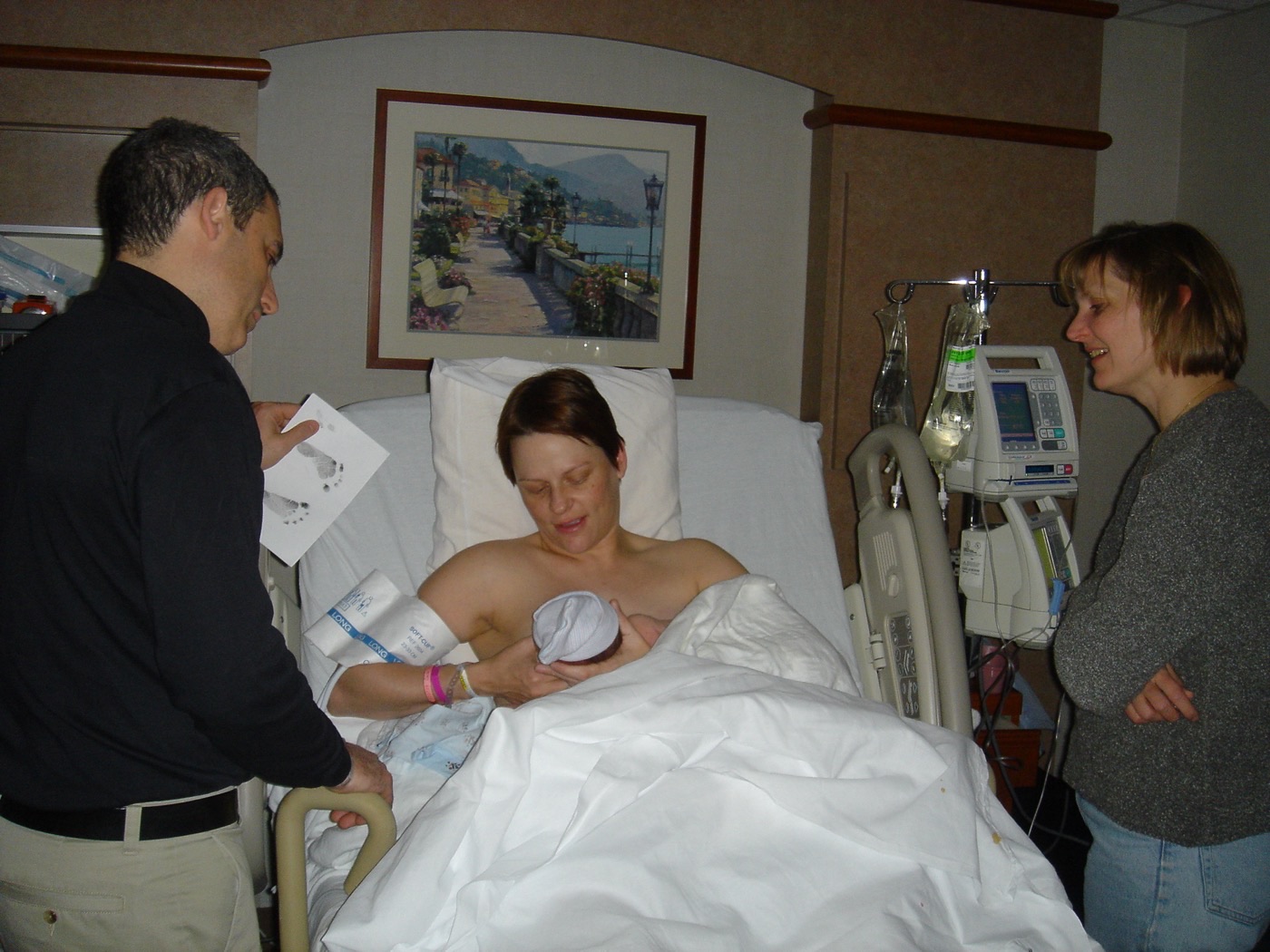 Puérpera segurando e amamentando o bebê junto ao corpo, com presença afetiva e cuidado preservados.