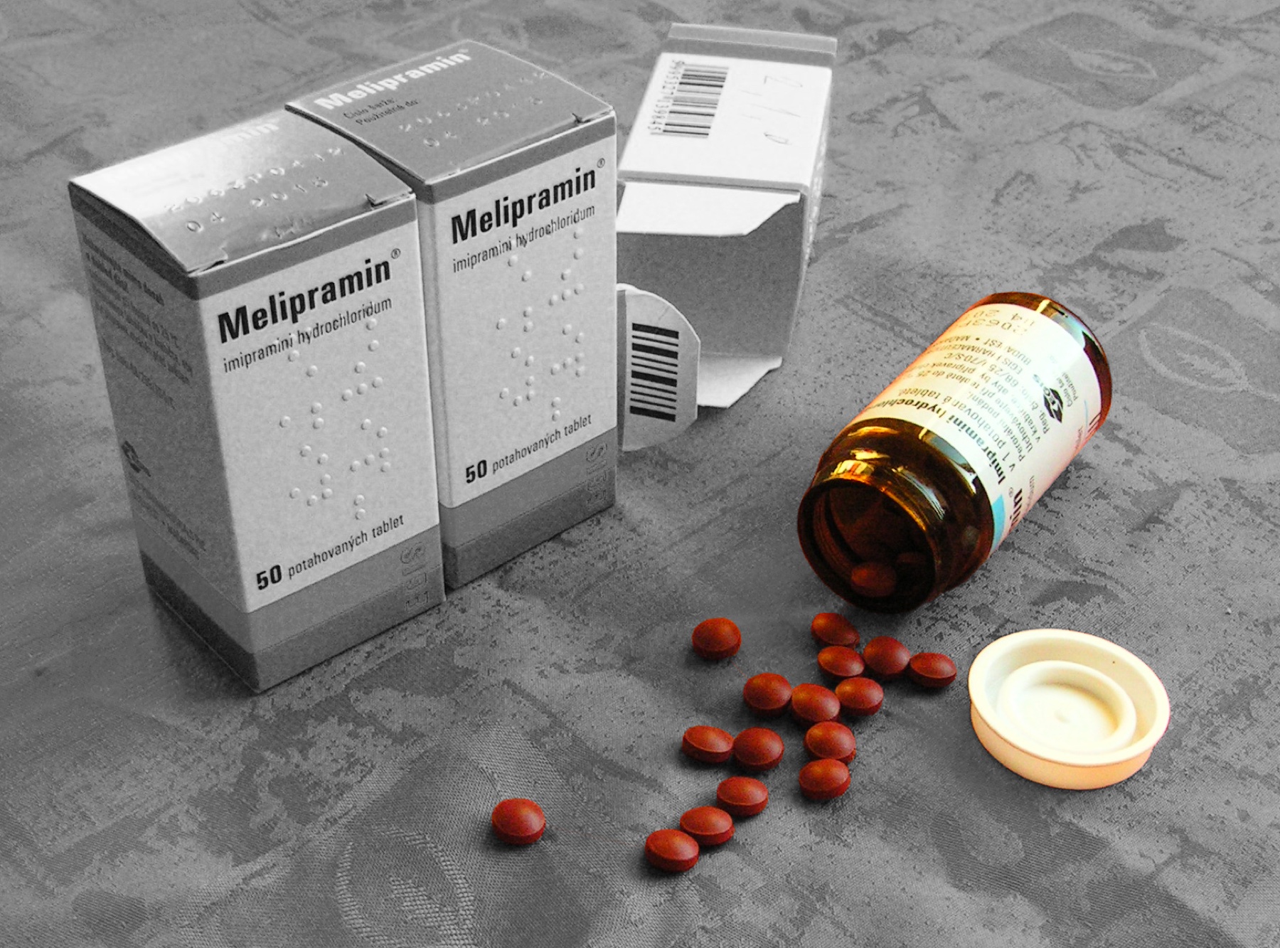 Embalagens de Melipramin (cloridrato de imipramina) acompanhadas de comprimidos revestidos vermelho-acastanhados.