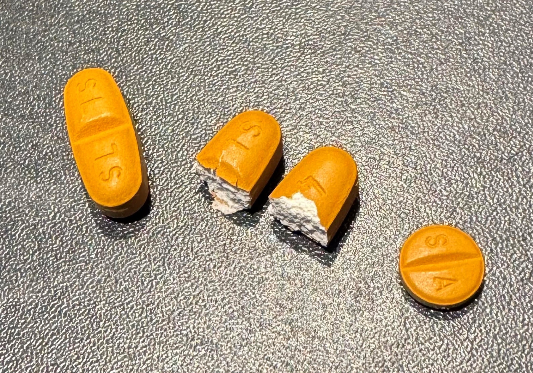 Comprimidos de imatinibe (Glivec) de 400 mg e 100 mg, um deles partido ao meio.