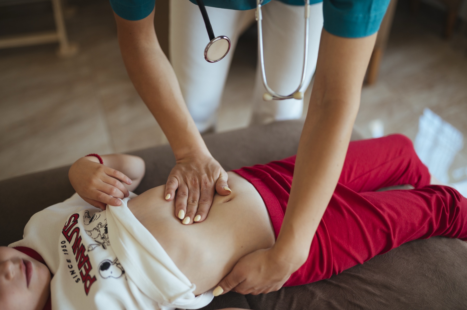 Pediatra examinando uma criança em consulta clínica, com a família ao lado, em cenário de avaliação do desenvolvimento.